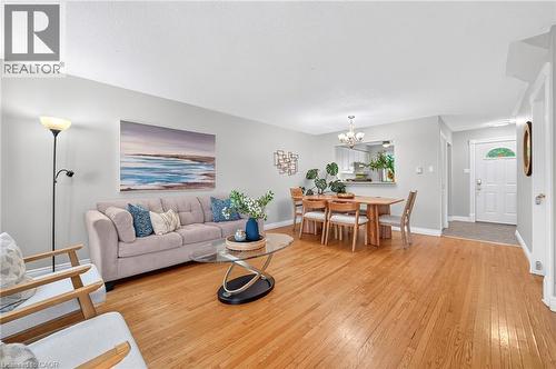 Hardwood-finish flooring, recessed kitchen pass-through, front entry door with decorative glass accent, and chandelier lighting over dining area - 1517 Elm Road Unit# 9, Oakville, ON 