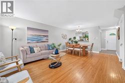Hardwood-finish flooring, recessed kitchen pass-through, front entry door with decorative glass accent, and chandelier lighting over dining area - 
