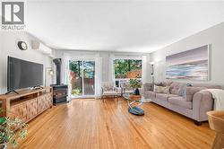 Hardwood flooring, wood-burning stove, sliding glass door, window, and wall-mounted air conditioning unit - 