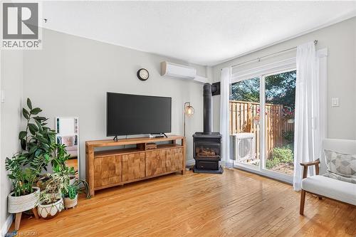 Hardwood flooring, sliding glass door leading to an outdoor area, a built-in wood-burning stove, and a wall-mounted air conditioning unit - 1517 Elm Road Unit# 9, Oakville, ON 