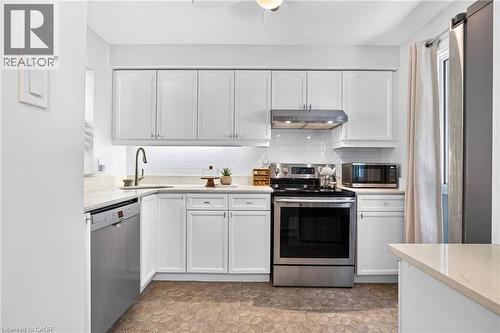 White cabinetry with brushed nickel hardware, stainless steel appliances, light-toned countertops, white subway tile backsplash, and hexagonal floor tiling - 1517 Elm Road Unit# 9, Oakville, ON 