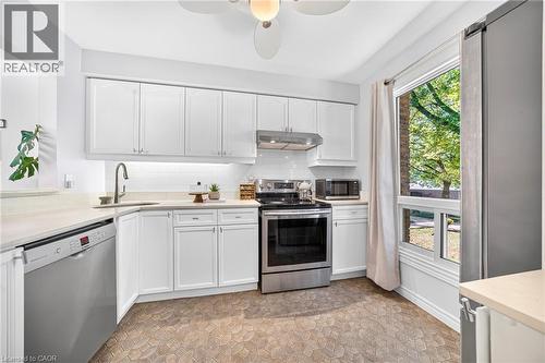 Kitchen featuring white cabinetry, light-colored countertops, stainless steel appliances, and a mosaic tile floor - 1517 Elm Road Unit# 9, Oakville, ON 