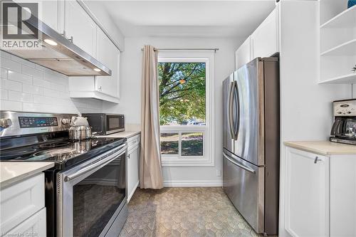 Kitchen featuring white cabinetry, stainless steel appliances, subway tile backsplash, and patterned floor tiling - 1517 Elm Road Unit# 9, Oakville, ON 