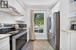 Kitchen featuring white cabinetry, stainless steel appliances, subway tile backsplash, and patterned floor tiling - 