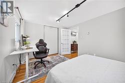Hardwood flooring, track lighting, white trim, white walls, and a white French door - 
