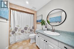 White vanity with black cabinet hardware, oval undermount sink, and a circular black-framed mirror - 