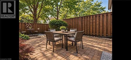 Paver patio with a privacy fence, surrounding green foliage, and natural landscaping - 1517 Elm Road Unit# 9, Oakville, ON 