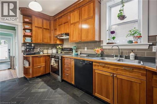 Custom cabinetry with integrated open shelving, and dark herringbone-patterned slate tile flooring - 58 Balmoral Avenue N, Hamilton, ON 
