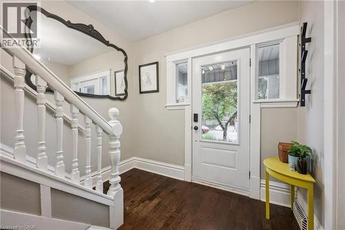 Hardwood flooring, white paneled entry door with glass inserts, white framed sidelight windows, and white painted staircase with balusters - 58 Balmoral Avenue N, Hamilton, ON 