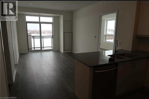 Kitchen with dishwasher, a peninsula, and dark wood-style flooring - 1105 Leger Way Unit# 329, Milton, ON 