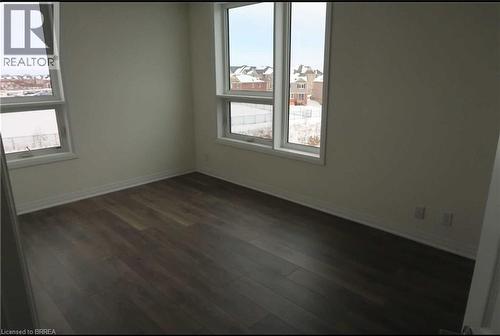 Unfurnished room featuring dark wood-type flooring and plenty of natural light - 1105 Leger Way Unit# 329, Milton, ON 