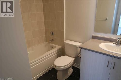 Bathroom featuring vanity, washtub / shower combination, and dark tile patterned floors - 1105 Leger Way Unit# 329, Milton, ON 