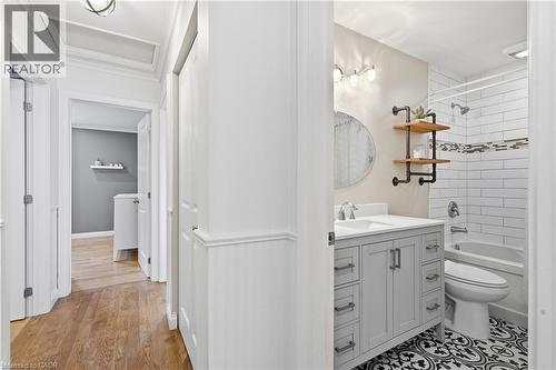 Bathroom featuring a single vanity with a solid surface countertop, white subway tile shower surround with an accent band, patterned floor tile, and a built-in tub - 72 Crestlynn Crescent, Simcoe, ON 