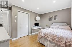 Recessed lighting illuminates this room, featuring wood-finish flooring, crown molding, and neutral wall tones - 