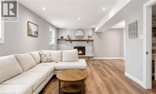 Spacious living area featuring wood-finish flooring, a white brick fireplace with a wood mantle, and recessed lighting - 72 Crestlynn Crescent, Simcoe, ON 