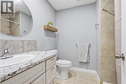 Bathroom featuring a white vanity with a patterned countertop, circular mirror, and tile flooring - 