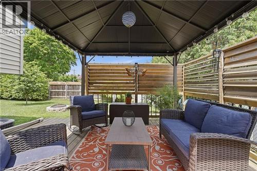 Expansive outdoor deck featuring a dark metal gazebo with string lighting, wood-finish slatted privacy screens, and a natural wood-finish deck surface - 72 Crestlynn Crescent, Simcoe, ON 