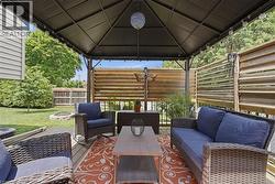 Expansive outdoor deck featuring a dark metal gazebo with string lighting, wood-finish slatted privacy screens, and a natural wood-finish deck surface - 