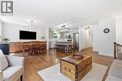 Open-concept living space featuring wood-finish flooring, white walls, and crown molding - 