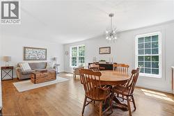 Open-concept living space featuring wood-finish flooring, white walls, and bright natural light from multiple windows - 