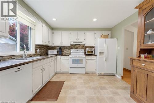 White cabinetry, stainless steel sink, tiled backsplash, and recessed lighting - 15 Mclaren Avenue N, Listowel, ON 