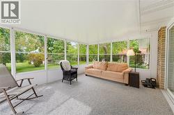 Enclosed patio featuring abundant natural light, a textured floor finish, and white paneled walls - 