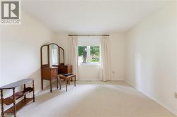 Soft neutral wall tones, window with white trim, and light carpeting throughout - 