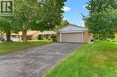 Brick exterior with light siding gable, attached garage, paved driveway, and mature landscaping - 15 Mclaren Avenue N, Listowel, ON 
