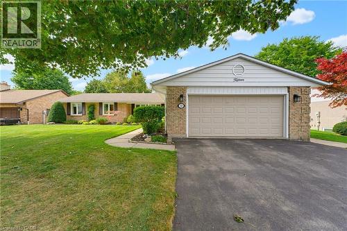 Paved driveway leading to a two-car garage with stone veneer accents and exterior wall sconces - 15 Mclaren Avenue N, Listowel, ON 