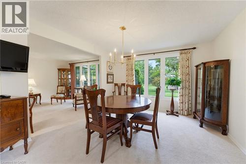 Spacious open-plan dining and living area featuring hardwood flooring, a round pedestal dining table with seating for multiple guests, and abundant natural light from multi-pane glass doors and window - 15 Mclaren Avenue N, Listowel, ON 