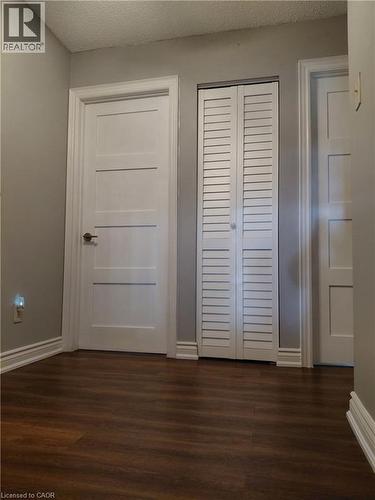Wood-finish flooring with white baseboards, modern interior doors with brushed nickel hardware, and white louvered closet doors - 244 Guildwood Drive, Hamilton, ON 