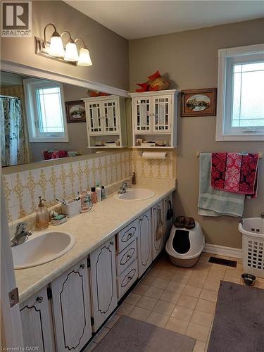 Dual vanity with integrated sinks, white cabinetry, and a full-width mirror - 244 Guildwood Drive, Hamilton, ON 
