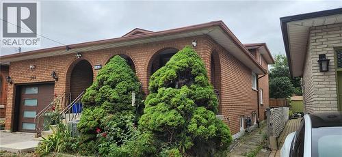 Brick exterior featuring arched entryways and a brown garage door with frosted glass inserts - 244 Guildwood Drive, Hamilton, ON 