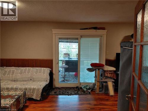 Wood-finish flooring, wood paneling, sliding glass door with exterior patio access, and a frosted glass-paneled entry door - 244 Guildwood Drive, Hamilton, ON 