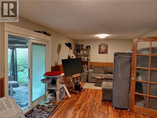 Wood-finish flooring throughout, sliding glass door with integrated blinds, and a paneled interior door with frosted glass inserts - 244 Guildwood Drive, Hamilton, ON 