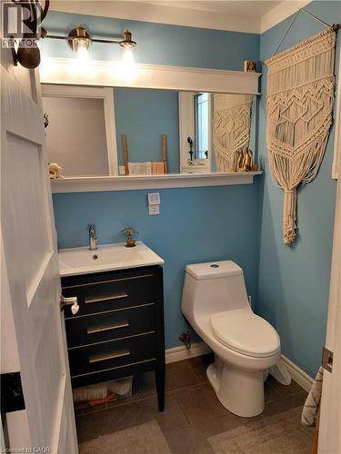 Bathroom with a modern vanity featuring a white basin sink, polished chrome faucet, and matte black cabinetry with horizontal gold-tone pulls - 244 Guildwood Drive, Hamilton, ON 