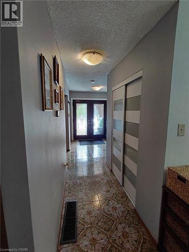 Hallway featuring patterned tile flooring, flush-mount lighting, and bi-fold closet doors with frosted panels - 244 Guildwood Drive, Hamilton, ON 