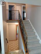 Carpeted staircase with an ornate wrought iron and wood handrail, leading to an upper landing with a matching wrought iron railing - 