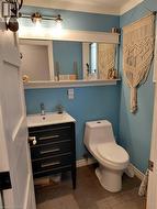 Modern vanity with a white rectangular sink, a wall-mounted light fixture, and a white toilet - 