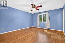 Wood-finish flooring, ceiling fan, single window, and white trim accents - 