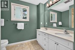 Dual vanity with white cabinetry and integrated sinks, a large mirror, and tiled flooring - 