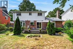 Expansive backyard with a wood deck, mature trees, and a brick exterior - 