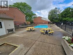 Outdoor swimming pool, fenced perimeter, concrete patio, planter boxes with foliage, adjacent brick building - 