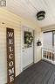 Covered front porch featuring wood-finish flooring, light-colored siding, and a white entry door with a glass pane - 17 Craigmiller Avenue, Hamilton, ON 