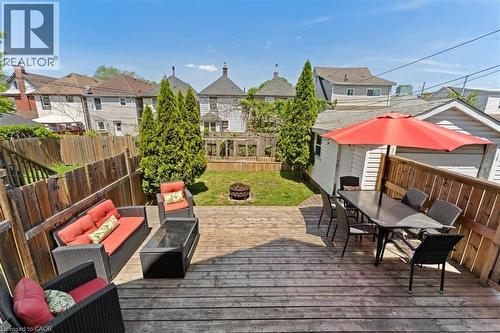 Expansive backyard featuring a multi-level wood deck, a grass lawn, and mature privacy trees - 17 Craigmiller Avenue, Hamilton, ON 