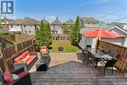 Expansive backyard featuring a multi-level wood deck, a grass lawn, and mature privacy trees - 