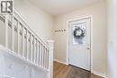 Entryway featuring a white paneled door with decorative glass, wood-finish flooring, and a staircase with white balusters and newel post - 17 Craigmiller Avenue, Hamilton, ON 