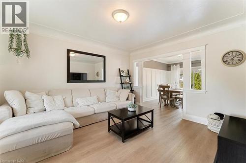 Living area featuring crown molding, light wood-finish flooring, and a cased opening to a dining area with board and batten wall treatment - 17 Craigmiller Avenue, Hamilton, ON 