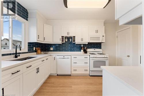 White kitchen featuring shaker-style cabinetry, a built-in wine rack, and a deep blue subway tile backsplash - 17 Craigmiller Avenue, Hamilton, ON 