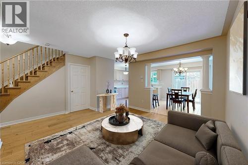 Wood-finish flooring throughout, spindle staircase, framed archway with decorative columns, and a dining area with sliding patio doors - 21 Eastview Gate Unit# 36, Brampton, ON 